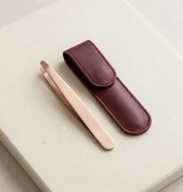 Rose Gold Slant Tweezers with Case Rose-gold slant-tip tweezers beside a burgundy protective case.